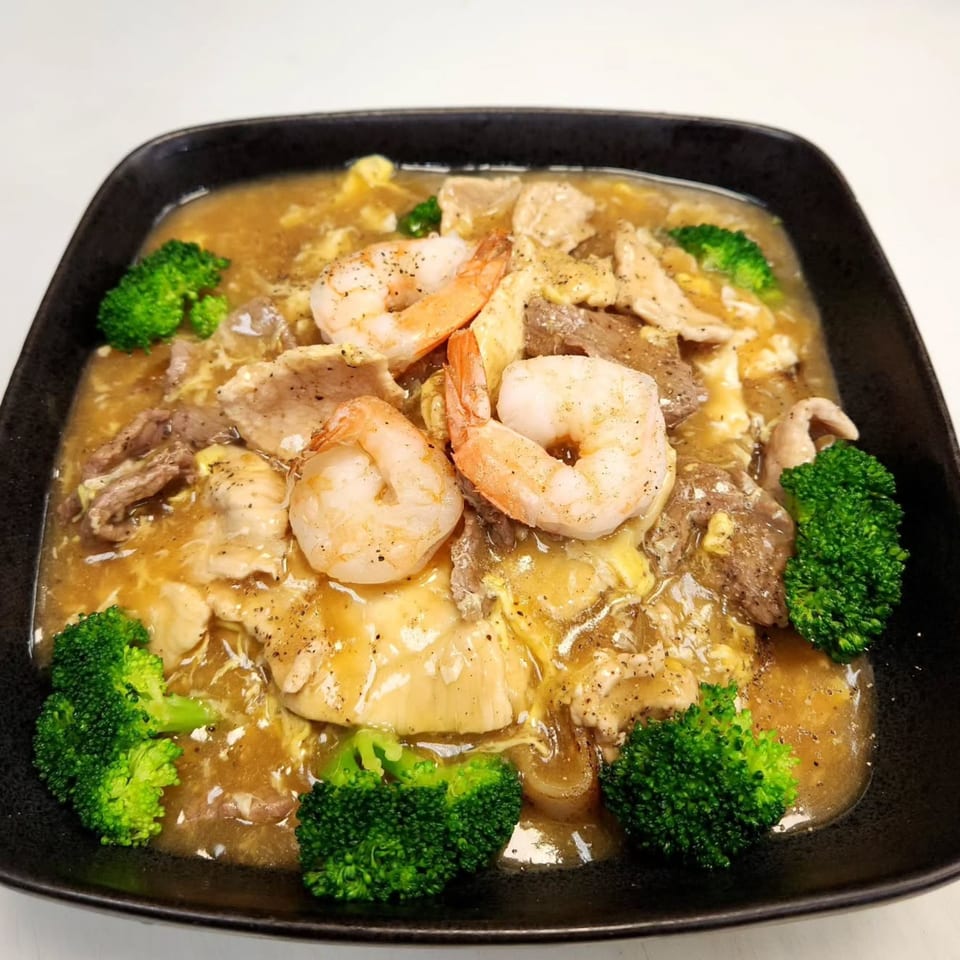 Noodle 501's gravy noodles with shrimp, beef, chicken, and broccoli in a black bowl.
