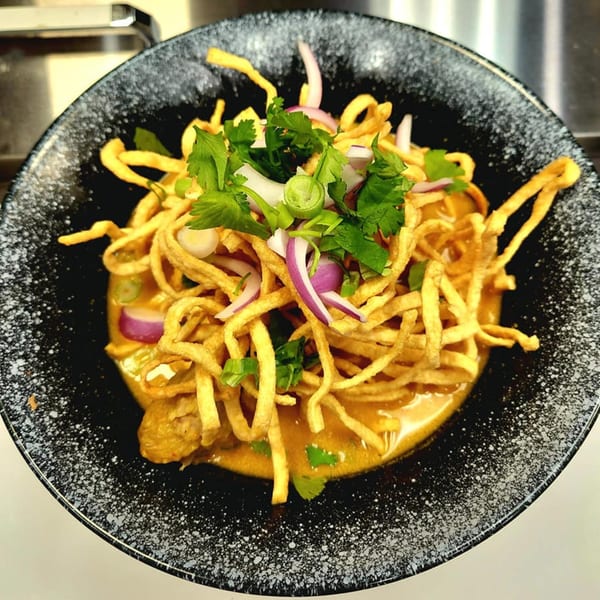 Noodle 501's Khao Soi, a rich curry noodle soup topped with crispy noodles, red onions, and cilantro.